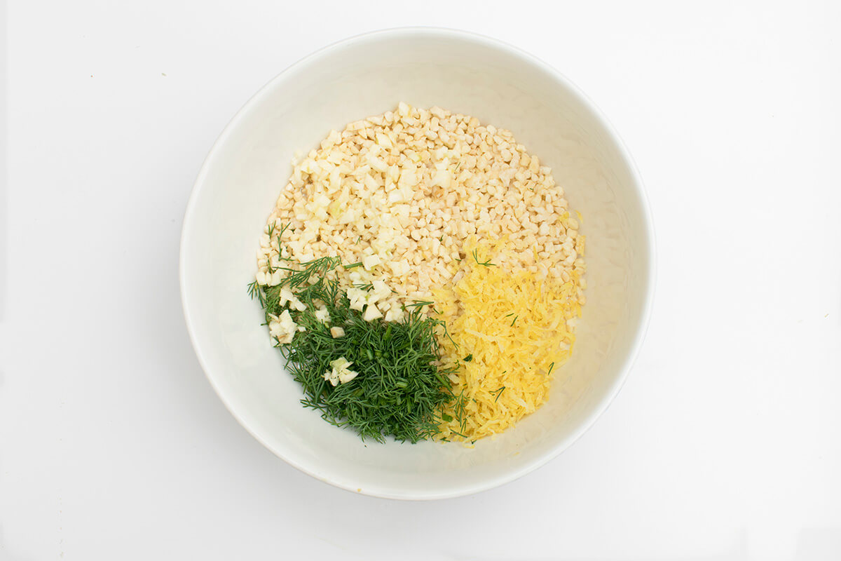 A bowl with chopped almonds, dill, garlic and oil
