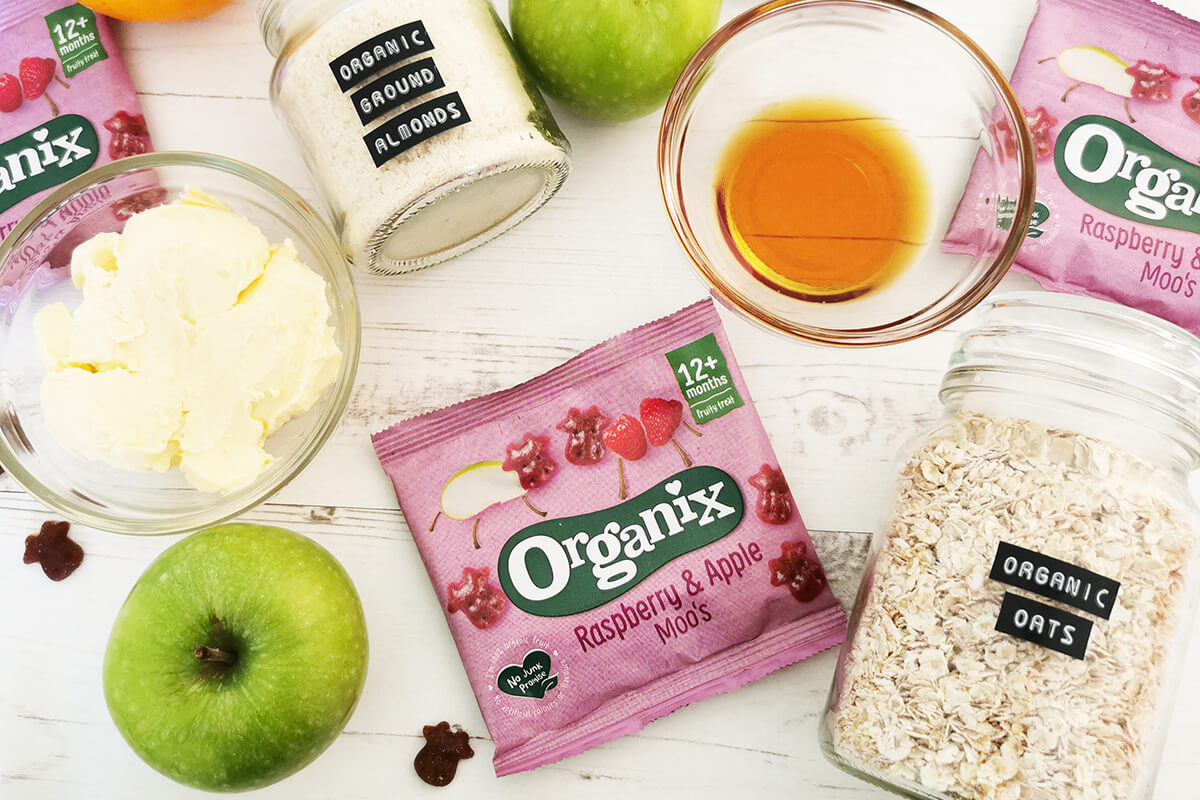 3 Organix Gummies packs next to a jar of oats, 2 green apples, a jar of ground almonds, an orange, a small bowl of butter and a small bowl of maple syrup