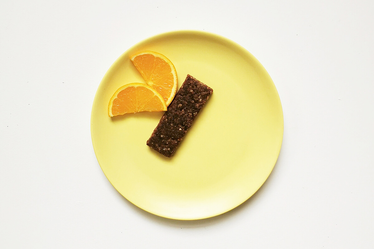 Oaty bar placed on plate with the two halved orange slices arranged to create wings