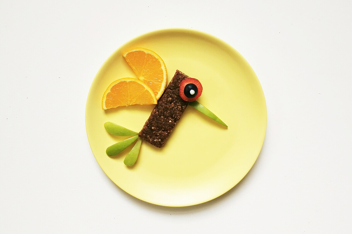 To create the birds eye, one strawberry slice is placed on the oaty bar with a halved blueberry and a dot of yoghurt on top