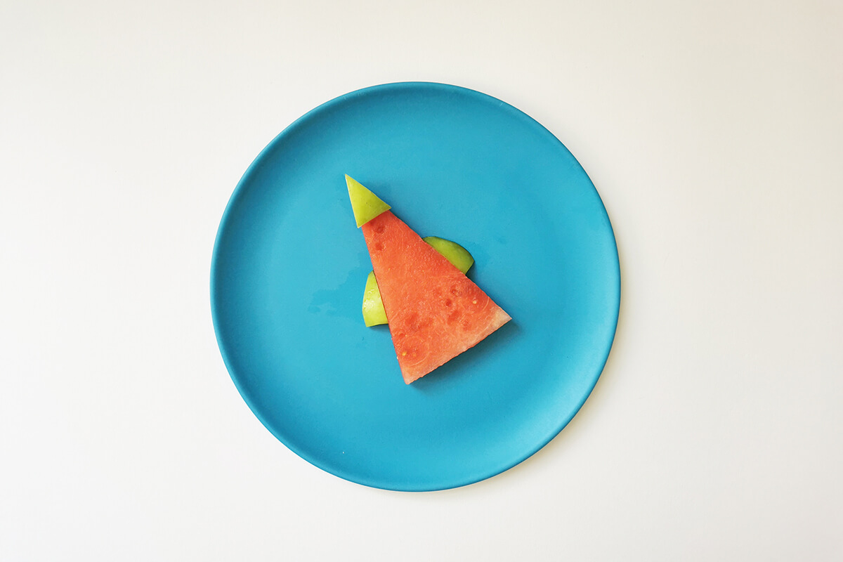 Watermelon triangle placed on plate with two apple fingers on either side and an apple triangle on top