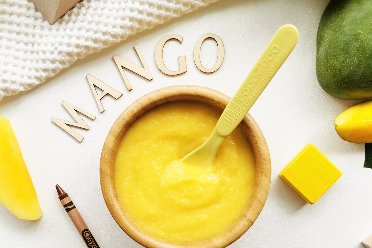 Mango puree in a bowl with some mango slices around it 
