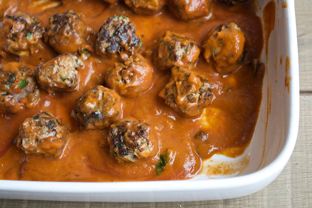 Meatballs, in an oven proof dish, topped with sauce