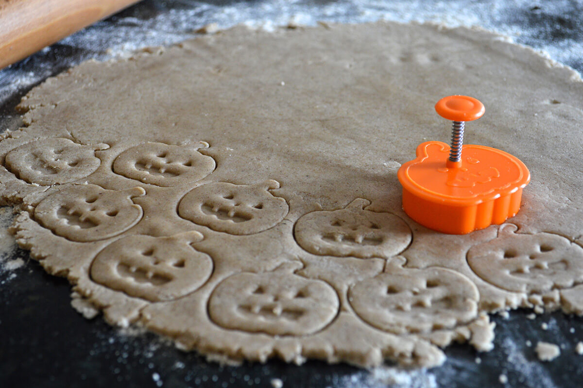 Biscuit dough being cut out with a pumpkin shaped cutter
