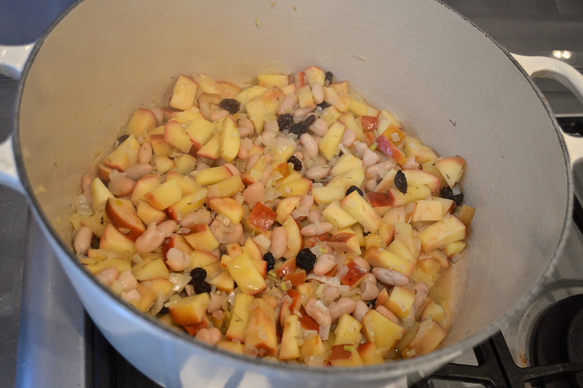 A saucepan of beans, onion and apple being simmered