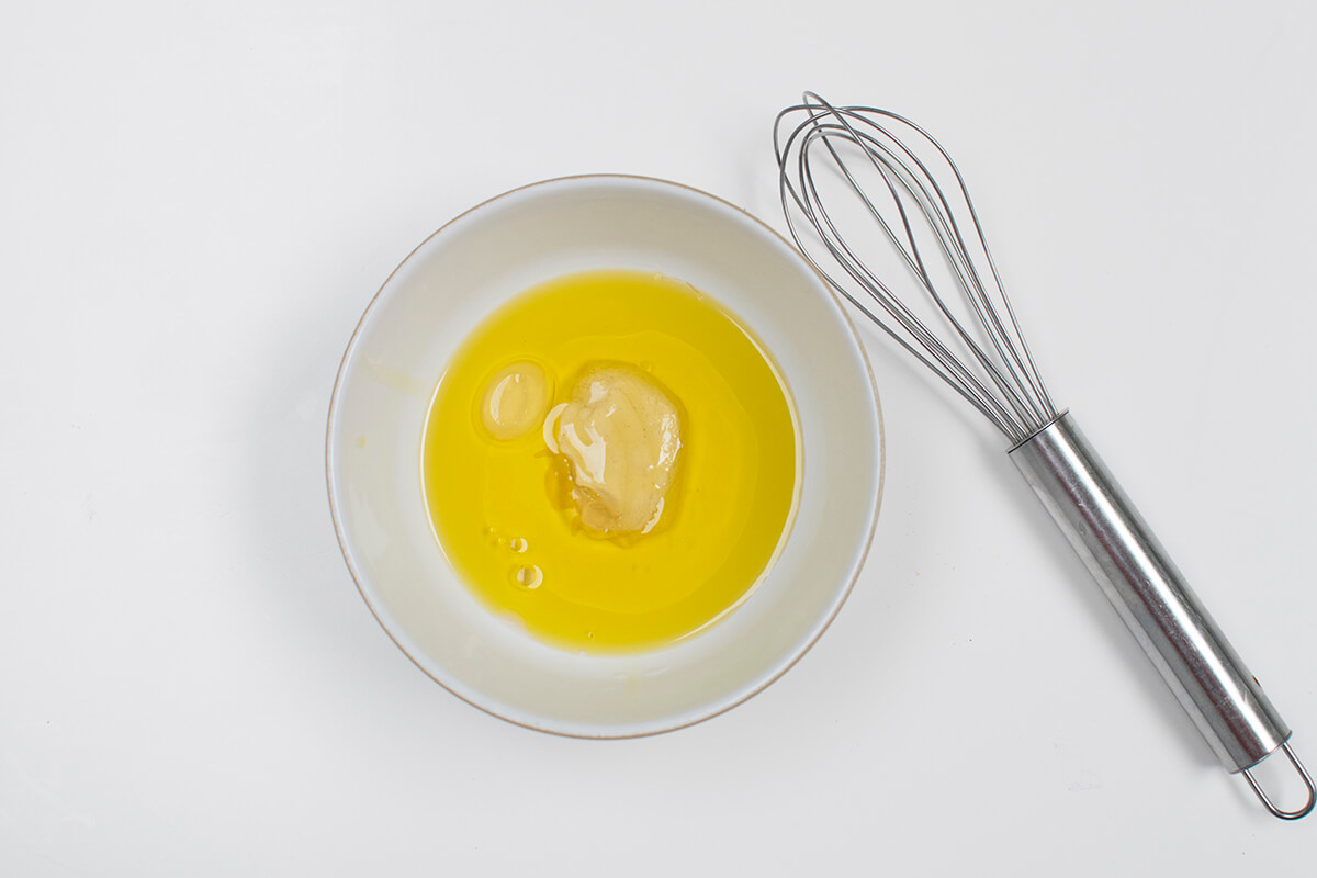 A bowl of Dijon mustard dressing next to a whisk