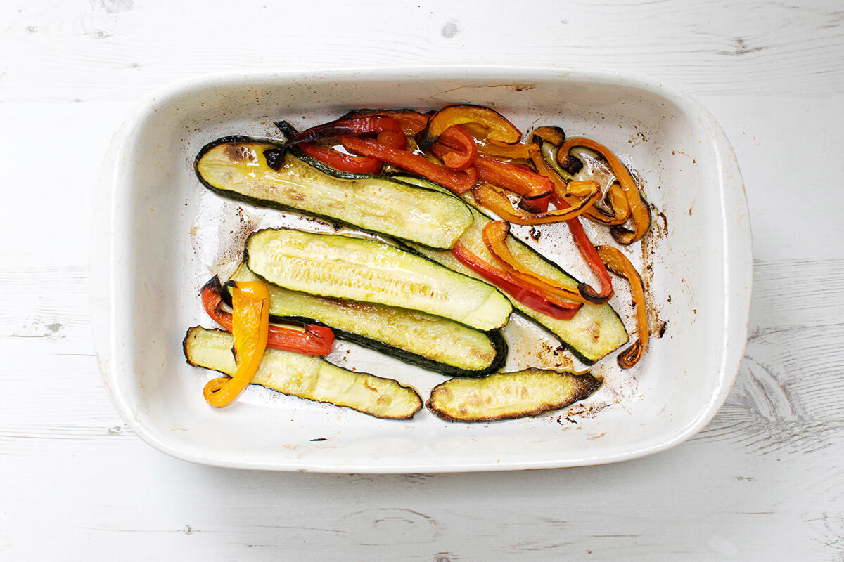 A baking tray with roasted sliced courgettes and peppers