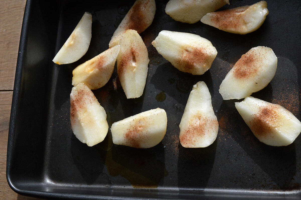 Pear slices sprinkled with cinnamon on a roasting tray
