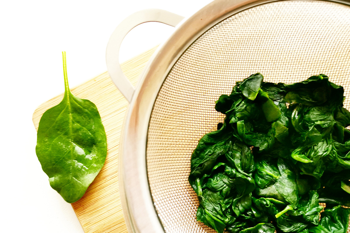 Blanched spinach leaves in a small bowl