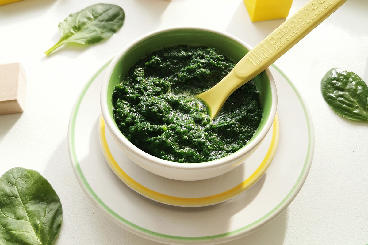 Spinach puree in a small bowl with some spinach leaves around it