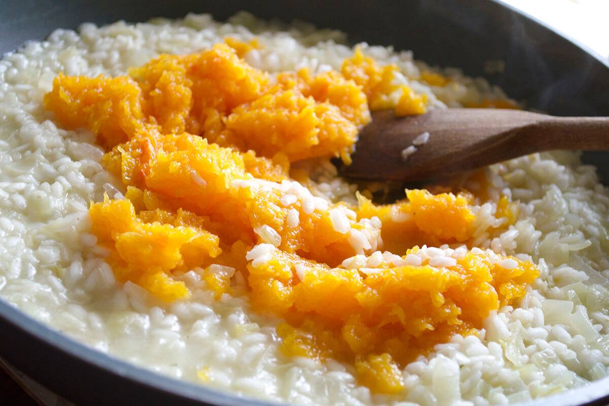 Pureed butternut squash being stirred into Arborio rice