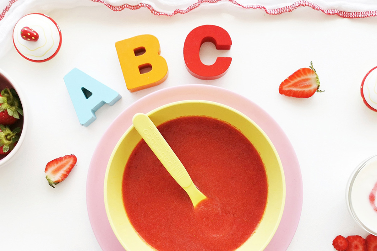 Strawy puree in a small bowl with sliced strawberries around it