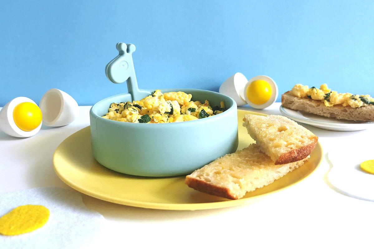 A bowl of scrambled eggs served with buttered toast
