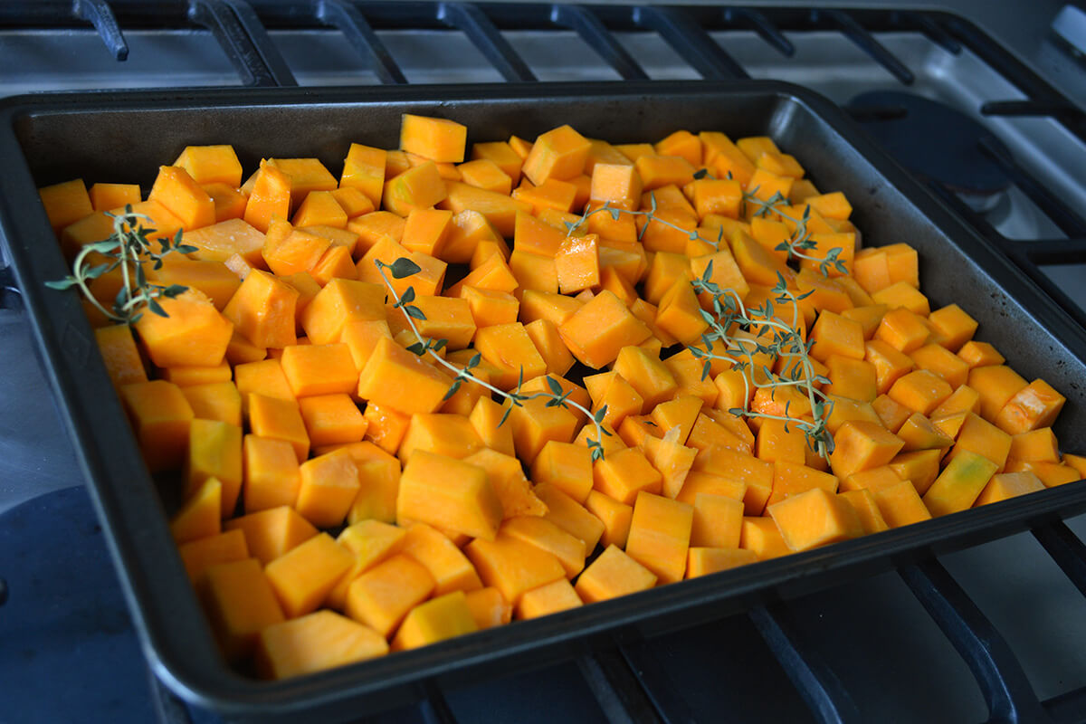 Peeled and diced butternut squash of a roasting tray, drizzled with olive oil and with some thyme