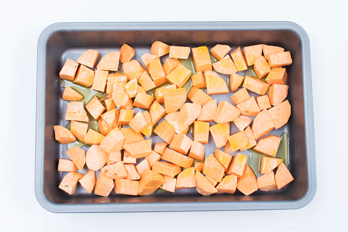 Diced sweet potato on a roasting tray and drizzled with oil