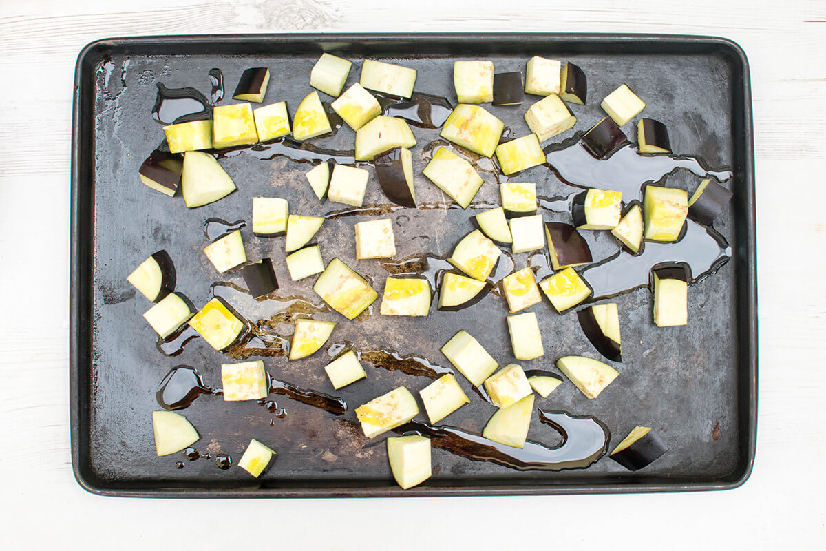 Chopped aubergine on a baking tray, drizzled with oil