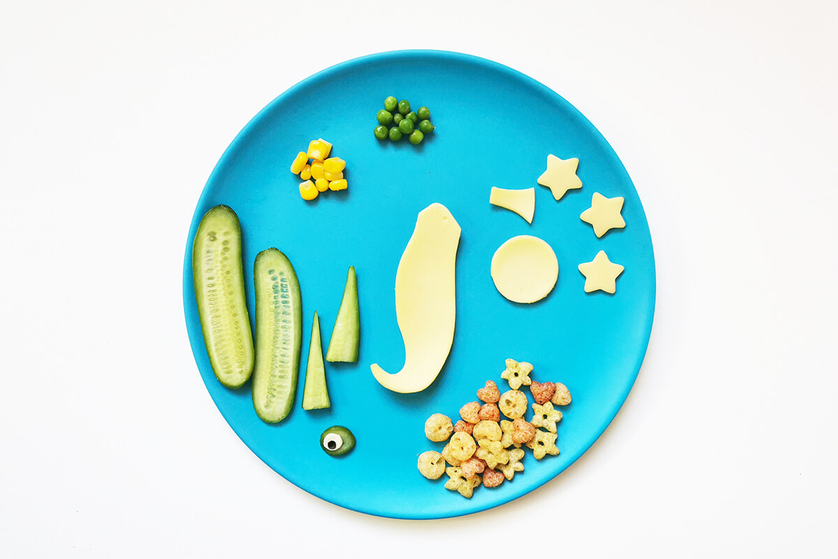 A plate of cucumber shapes, cheese shapes, peas, sweetcorn and a bag of Organix veggie mini mix ups