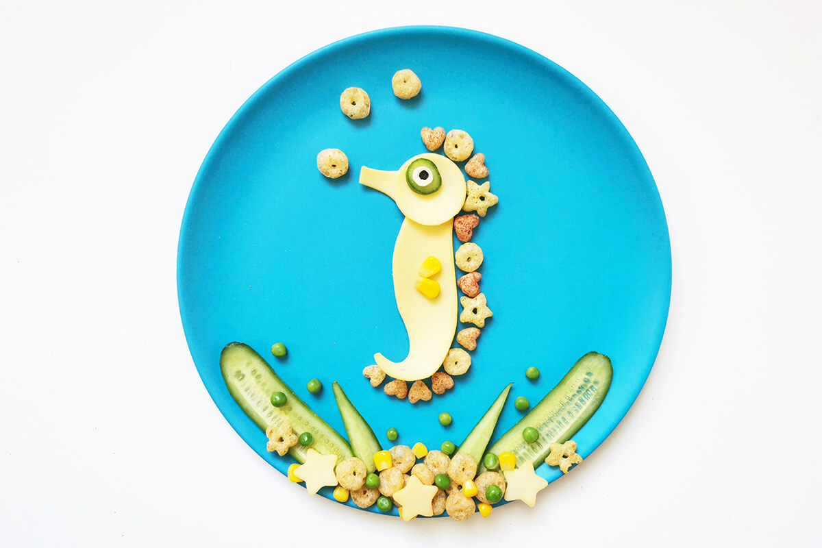To complete the veggie seahorse fun plate, sliced cucumber, peas, sweetcorn, mini cheese stars and veggie mini  mix ups are arranged at the bottom of the plate to create a coral reef