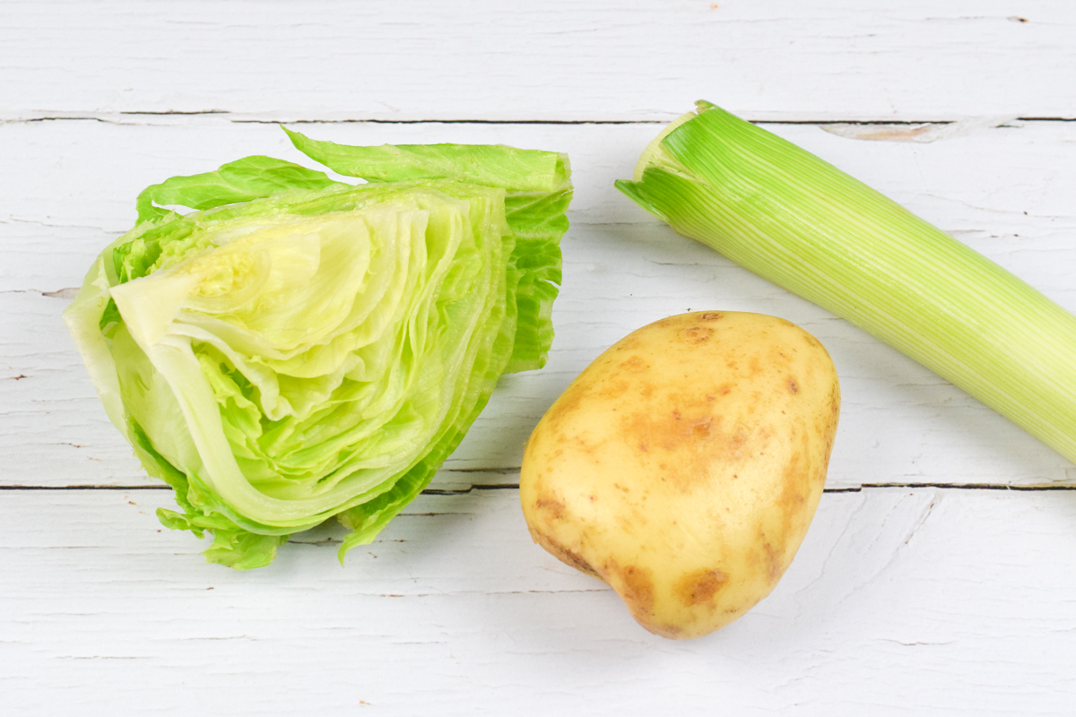 A table with a 1/4 of lettuce, a potato and a leek